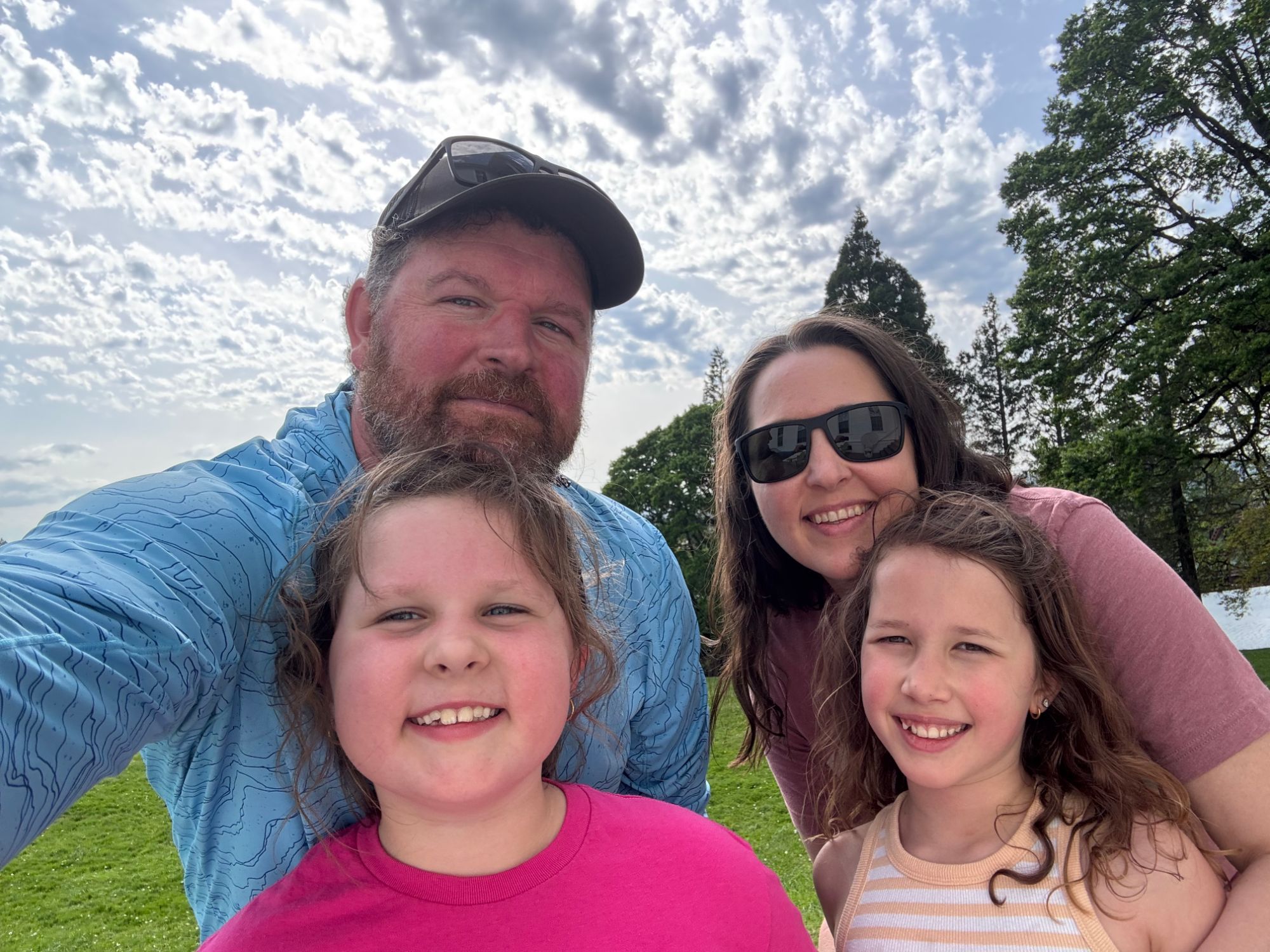 The Howe family, two parents and their two daughters, smiling together outdoors